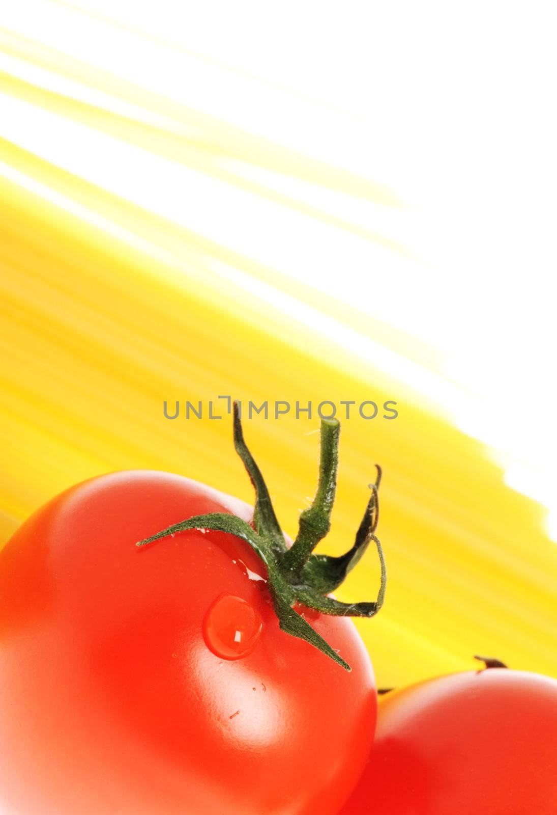 Tomato with drops and uncooked spaghetti noodleson background