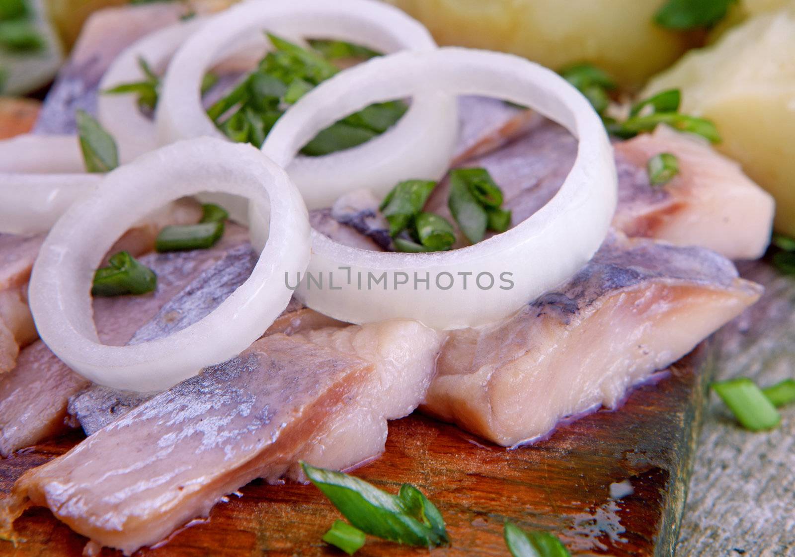 Herring with potato and  onion on a wooden table