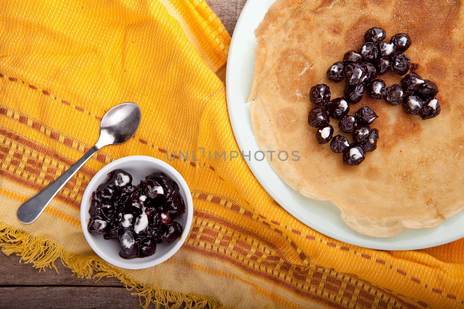 Crepes on the tablecloth with cherry and with sour cream