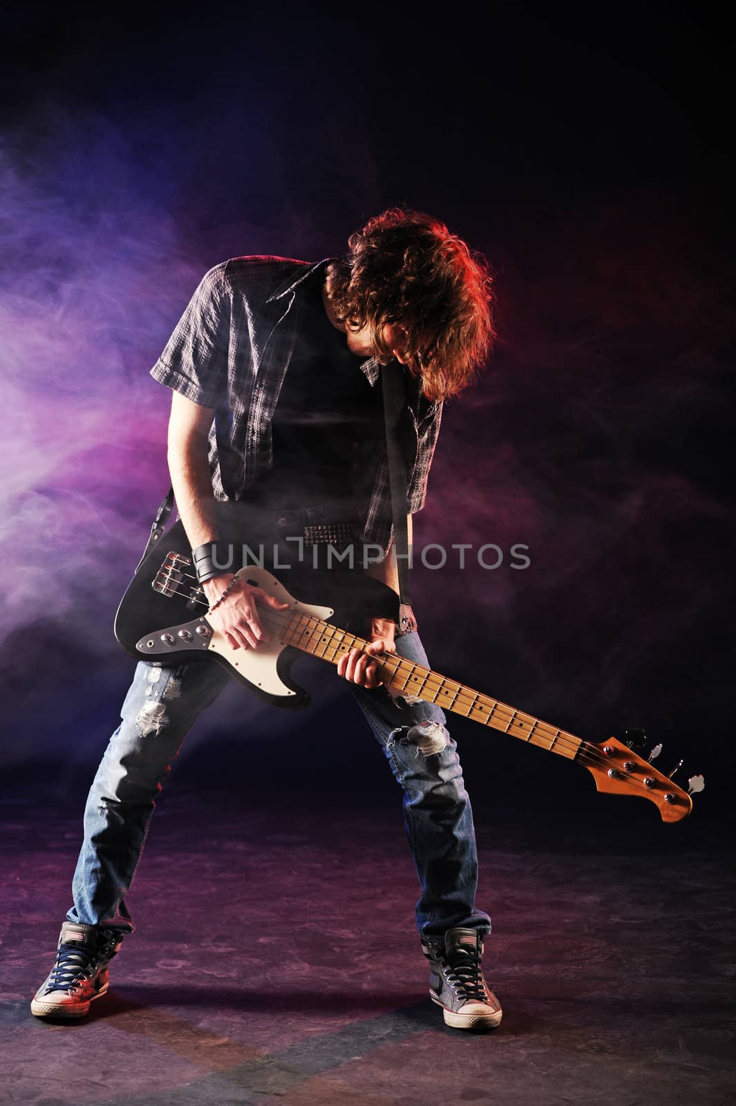 rock bassist plays his bass on a dark background by stokkete