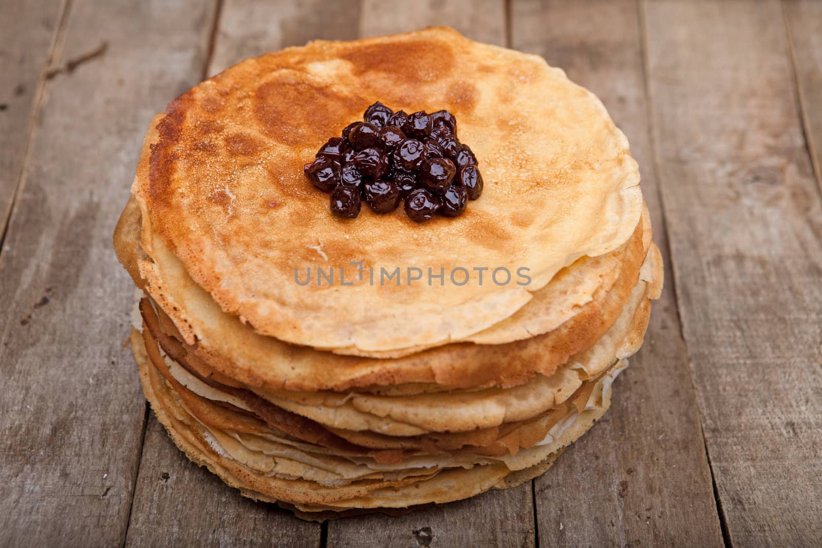 Crepes on the wooden table with cherry