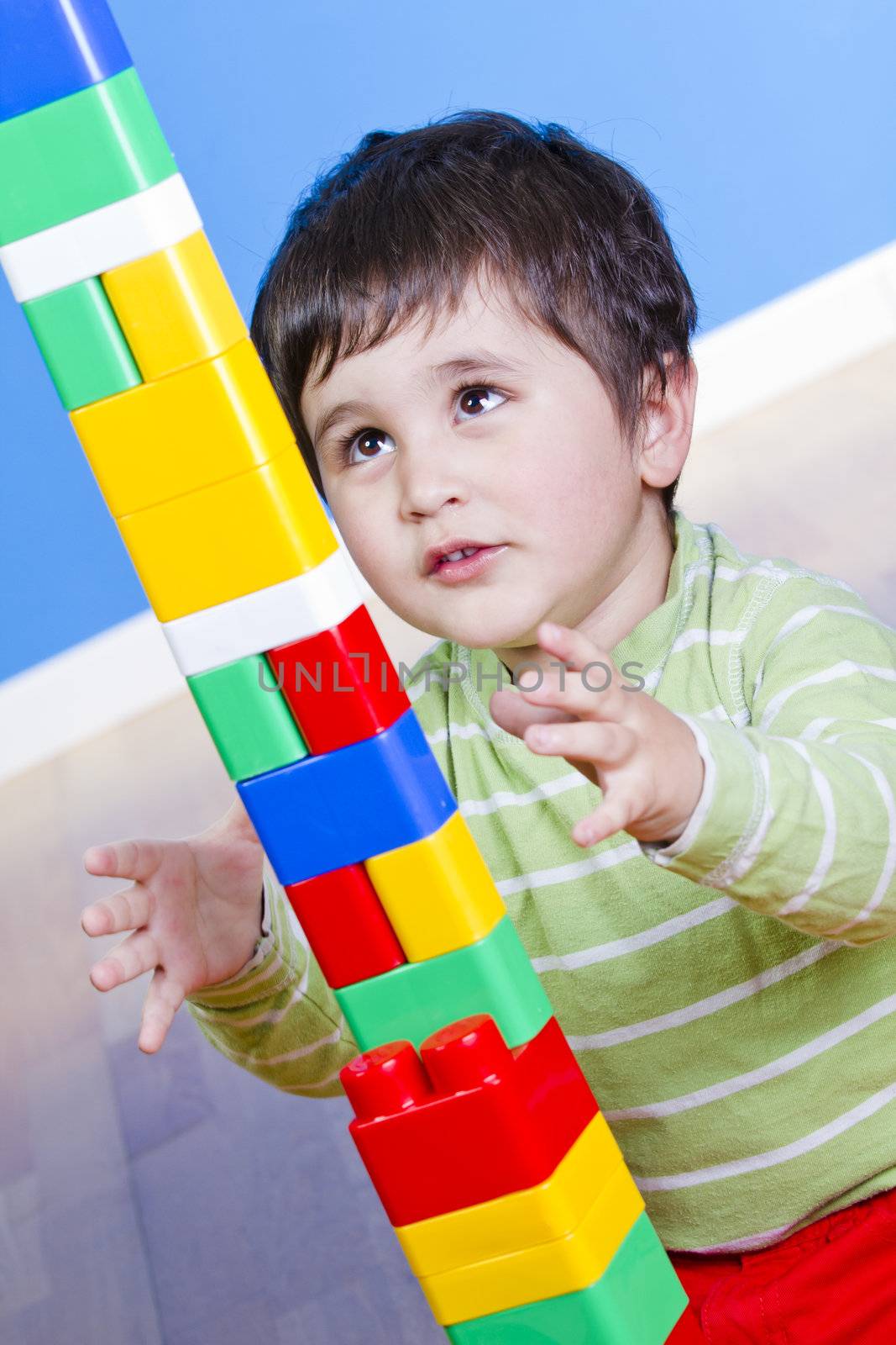 Funny little boy playing with plastic colorful blocks, studio shot