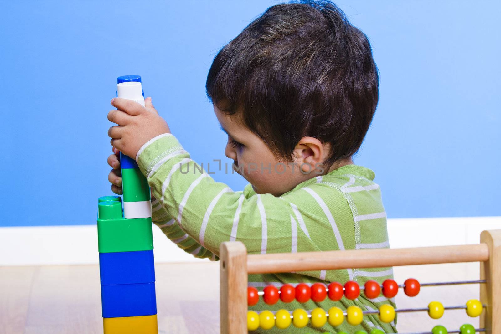 Baby is playing with educational toys over wooden background