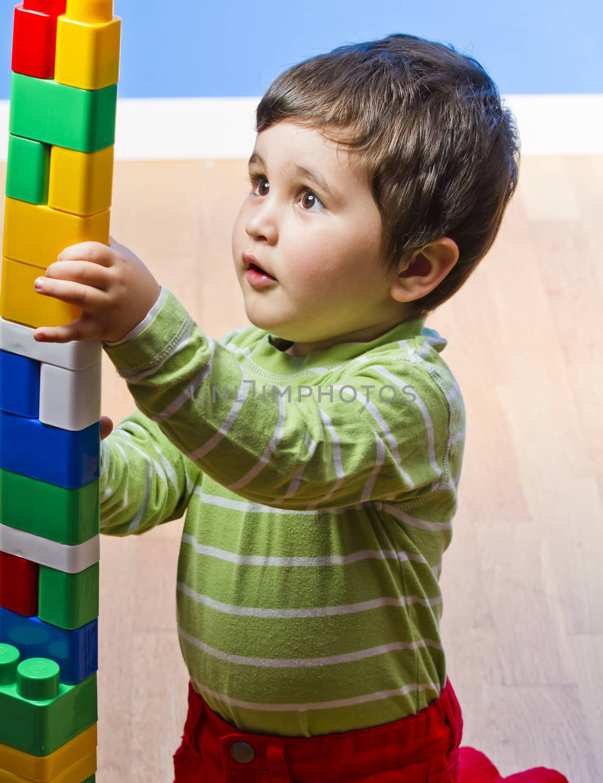 Cute little brunette baby playing with colorful blocks