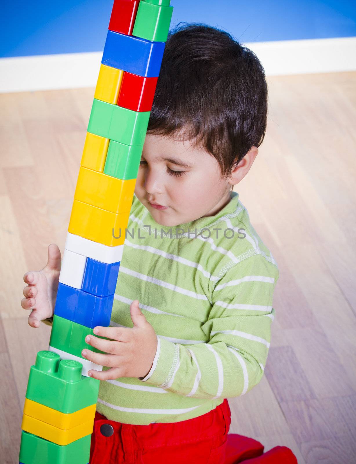 Little baby boy (2 years old) playing with toy blocks. Funny education