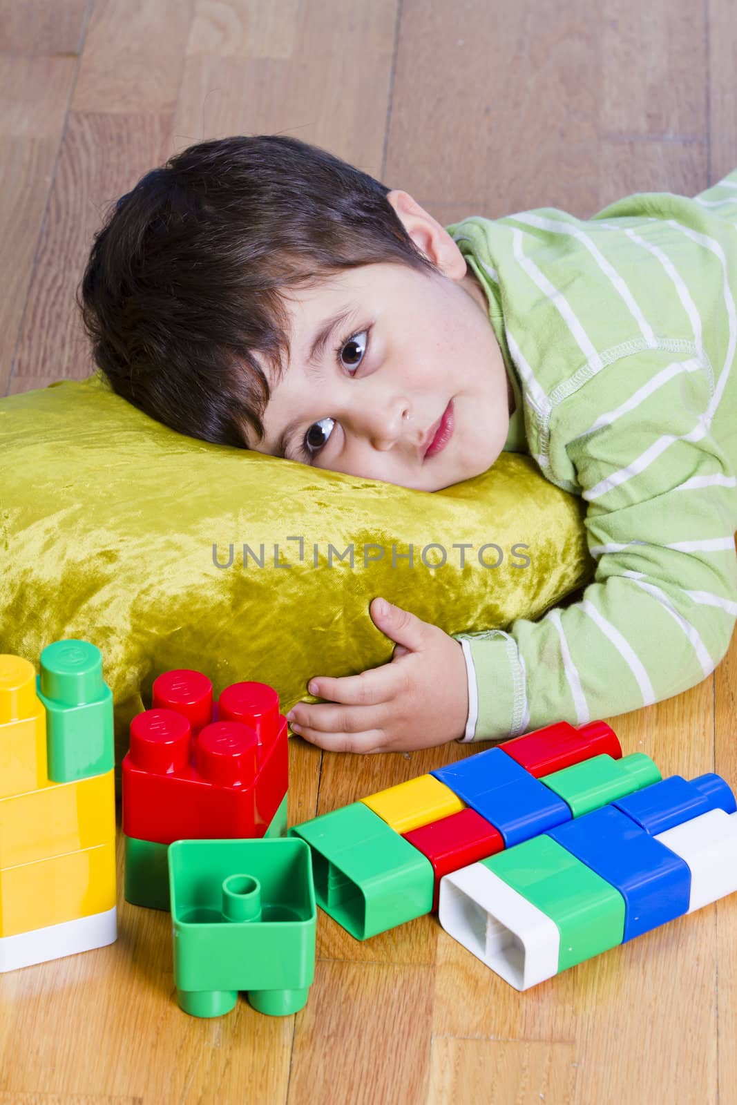 Cute little brunette child is playing with toys while sitting on by FernandoCortes