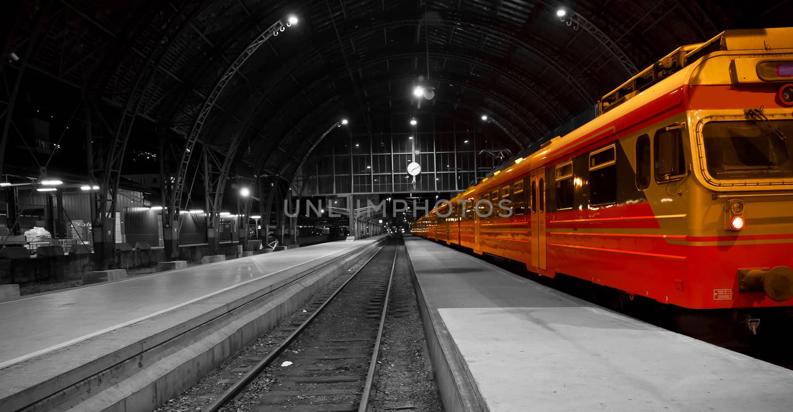 A picture of a train in a railwaystation, black white photo.With the train in color