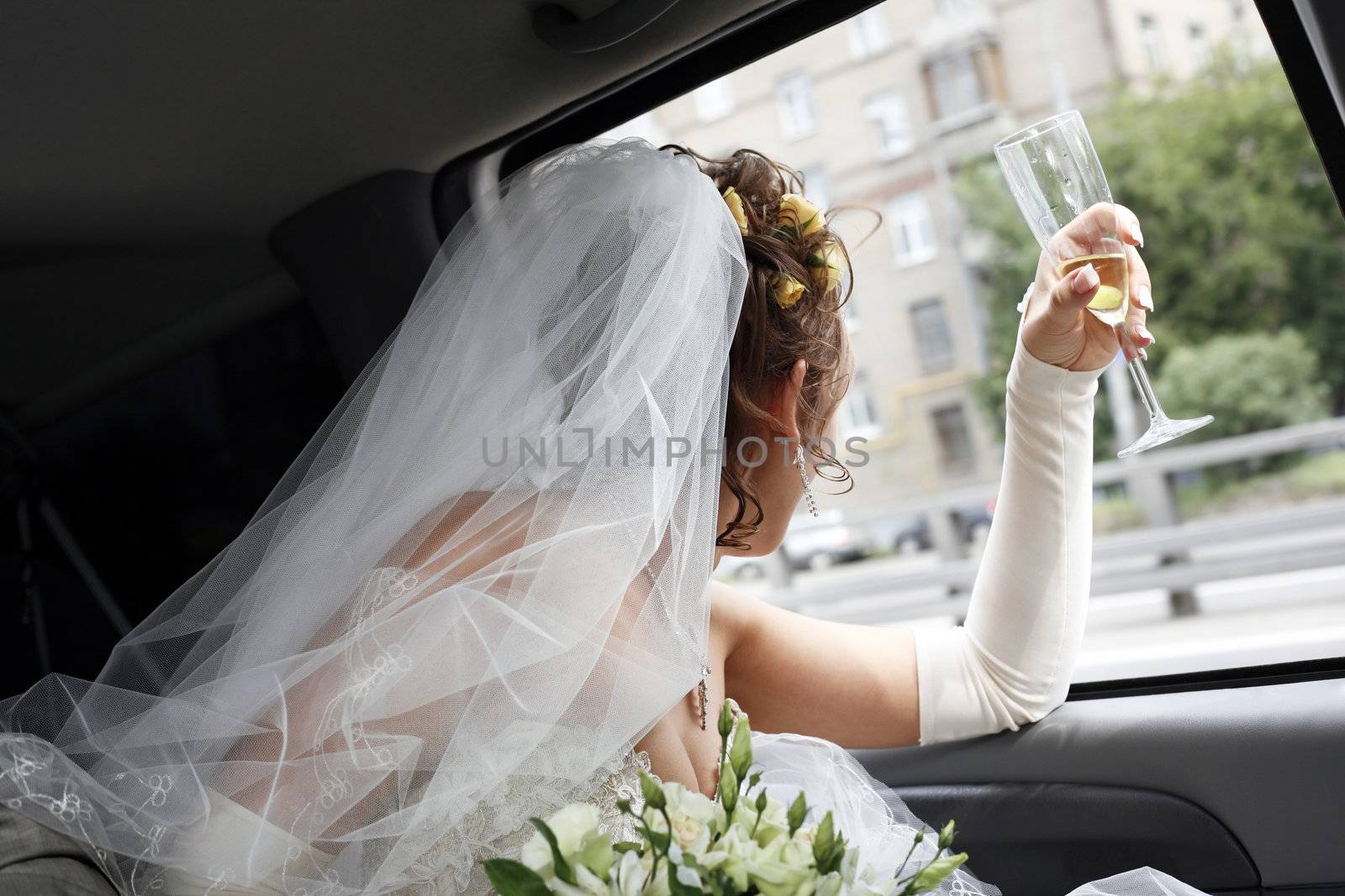 The bride looks in a window of the automobile