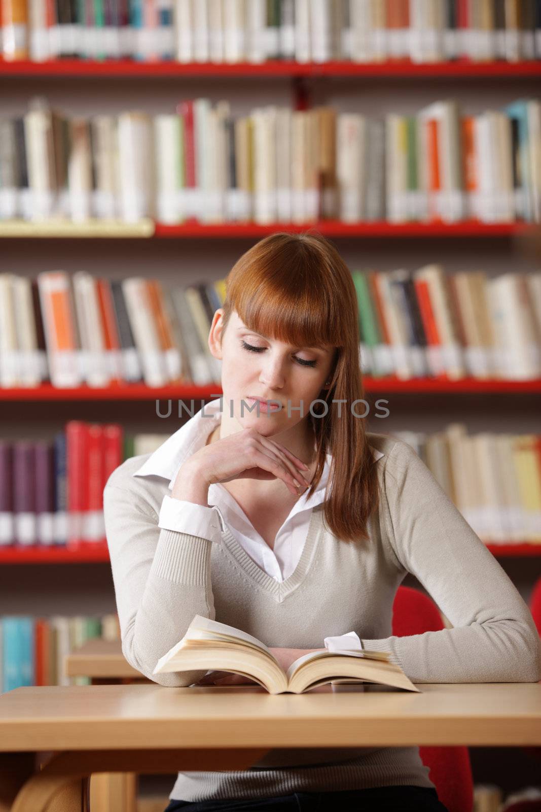 Young student in a library  by stokkete