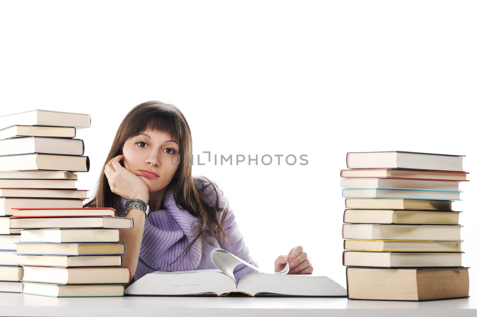 Tired of studies, young Woman is sitting on her desk with books  by stokkete