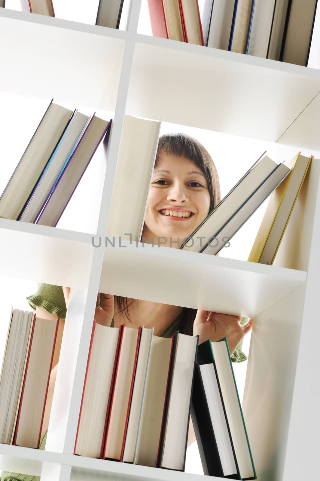 young Woman looking for a book at the library by stokkete