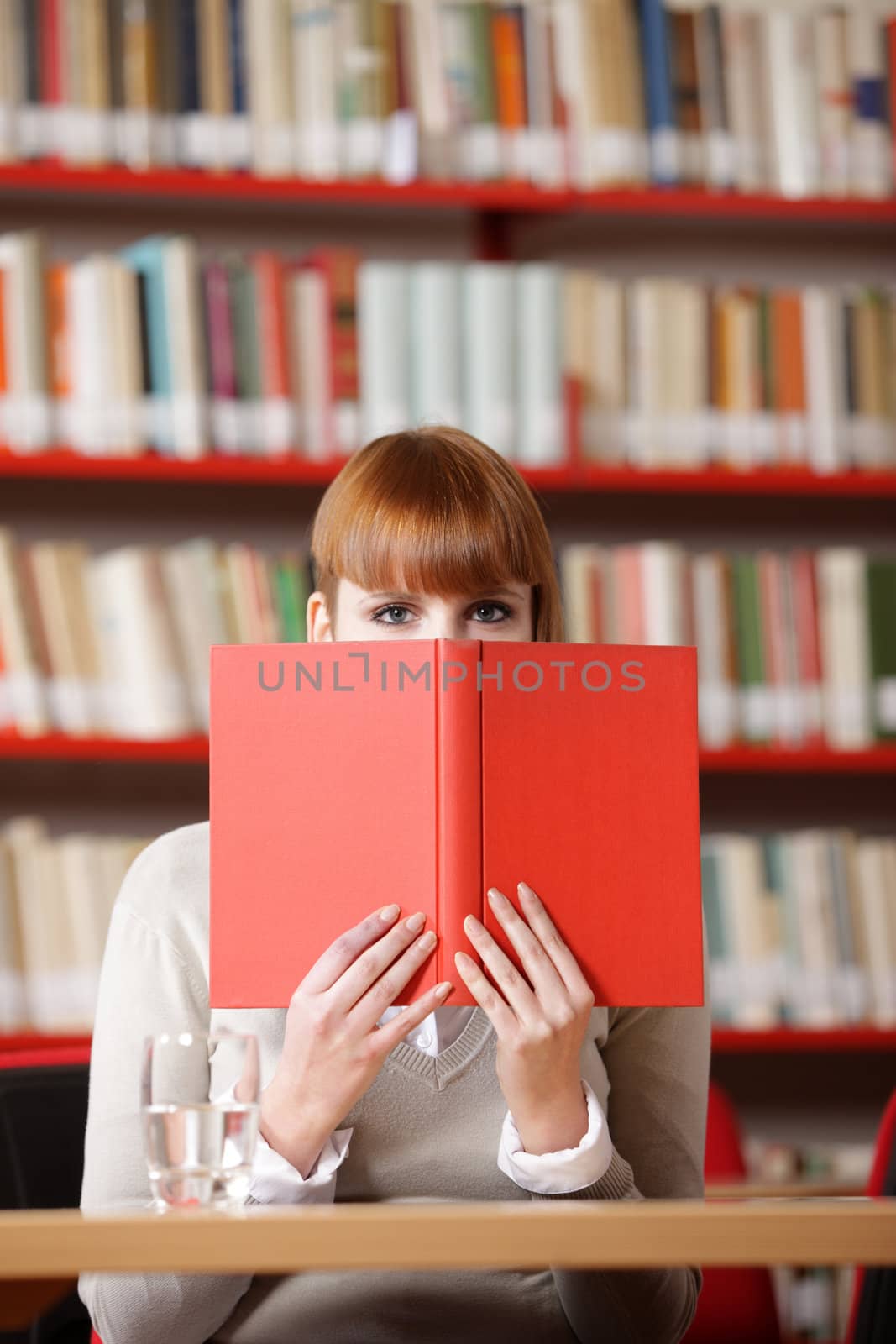 Girl hiding behind the book on library 
