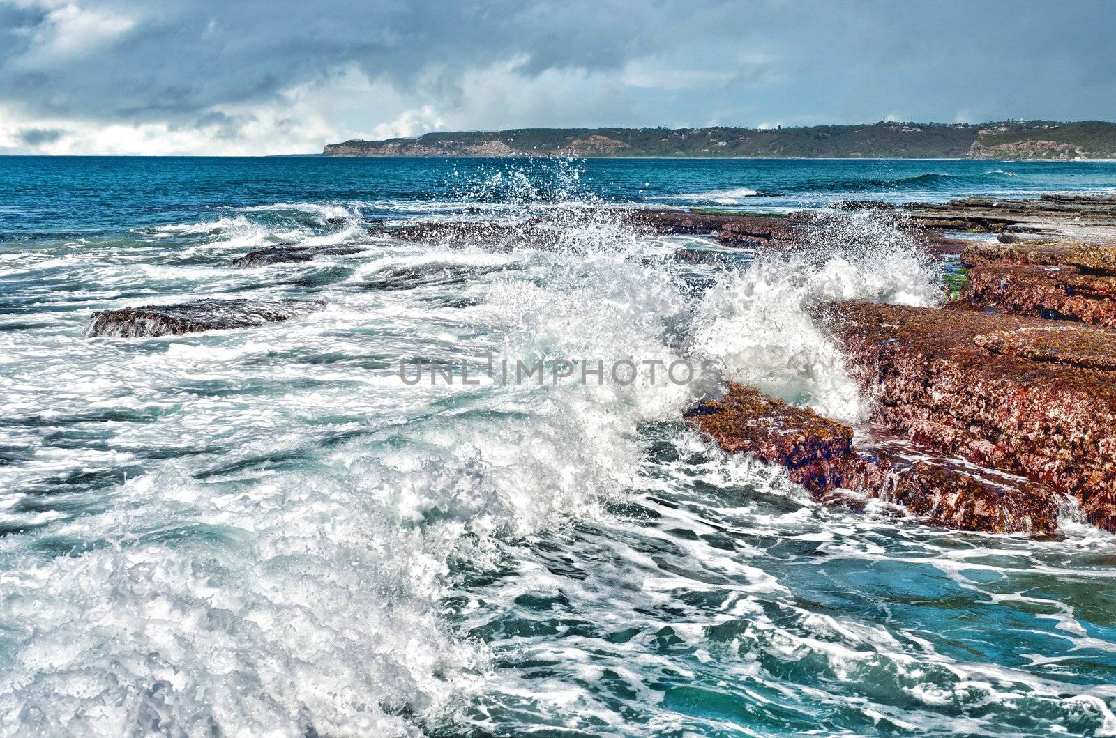 strong waves crashing onto rocks at the coast