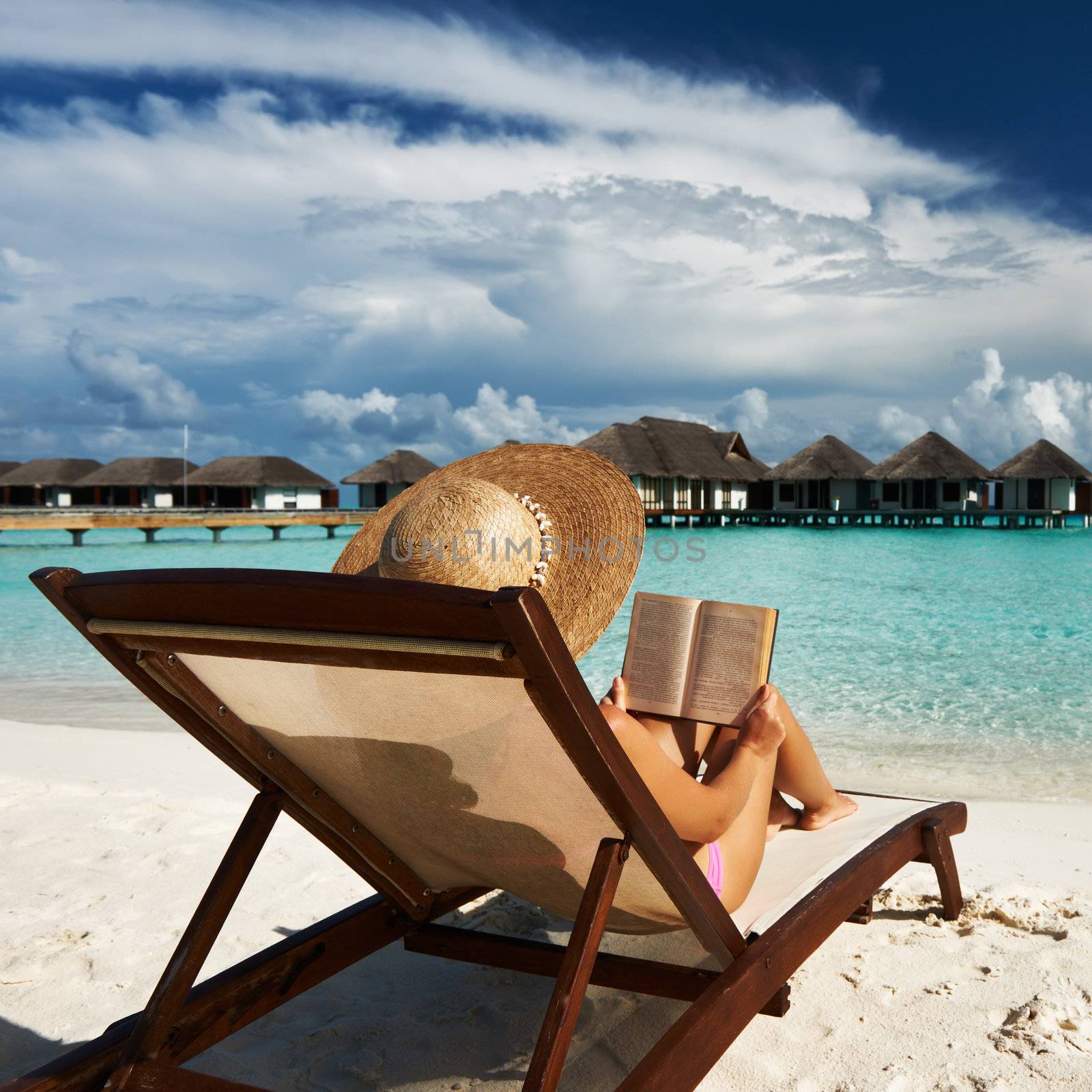 Young woman reading a book at beach by haveseen