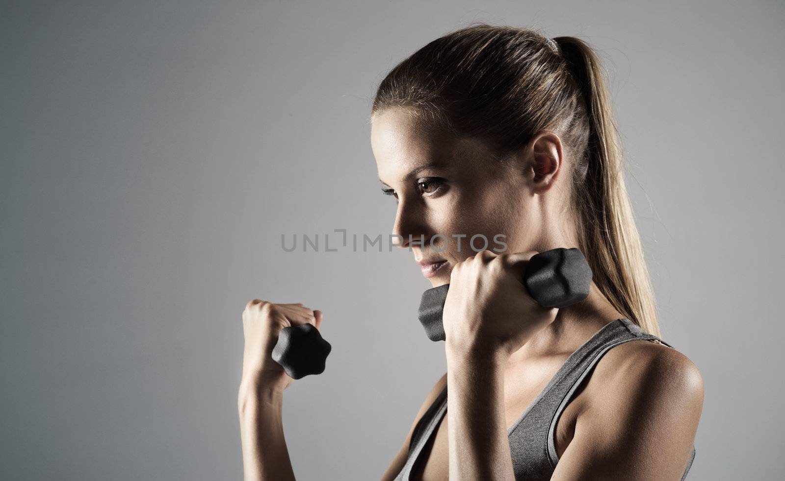 A beautiful woman raises with dumbbells 