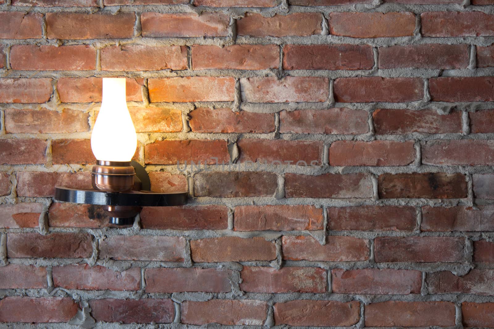 Old-fashioned sconce light on a brick wall.