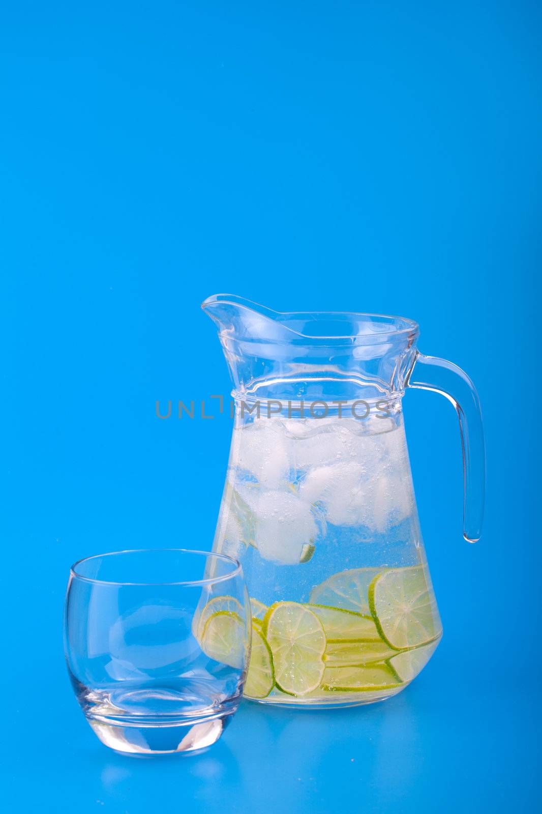 Lemonade Pitcher with ice on blue background by motorolka