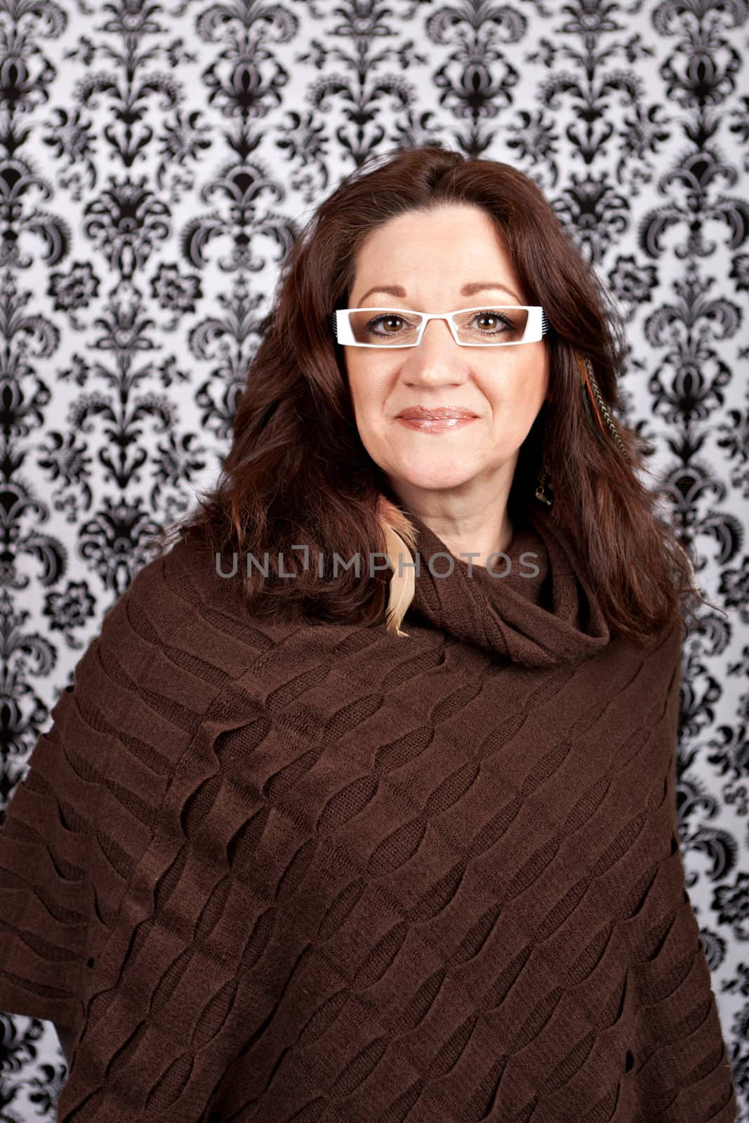 Brunette middle aged woman weather white framed glasses and feather hair extensions and accessories.