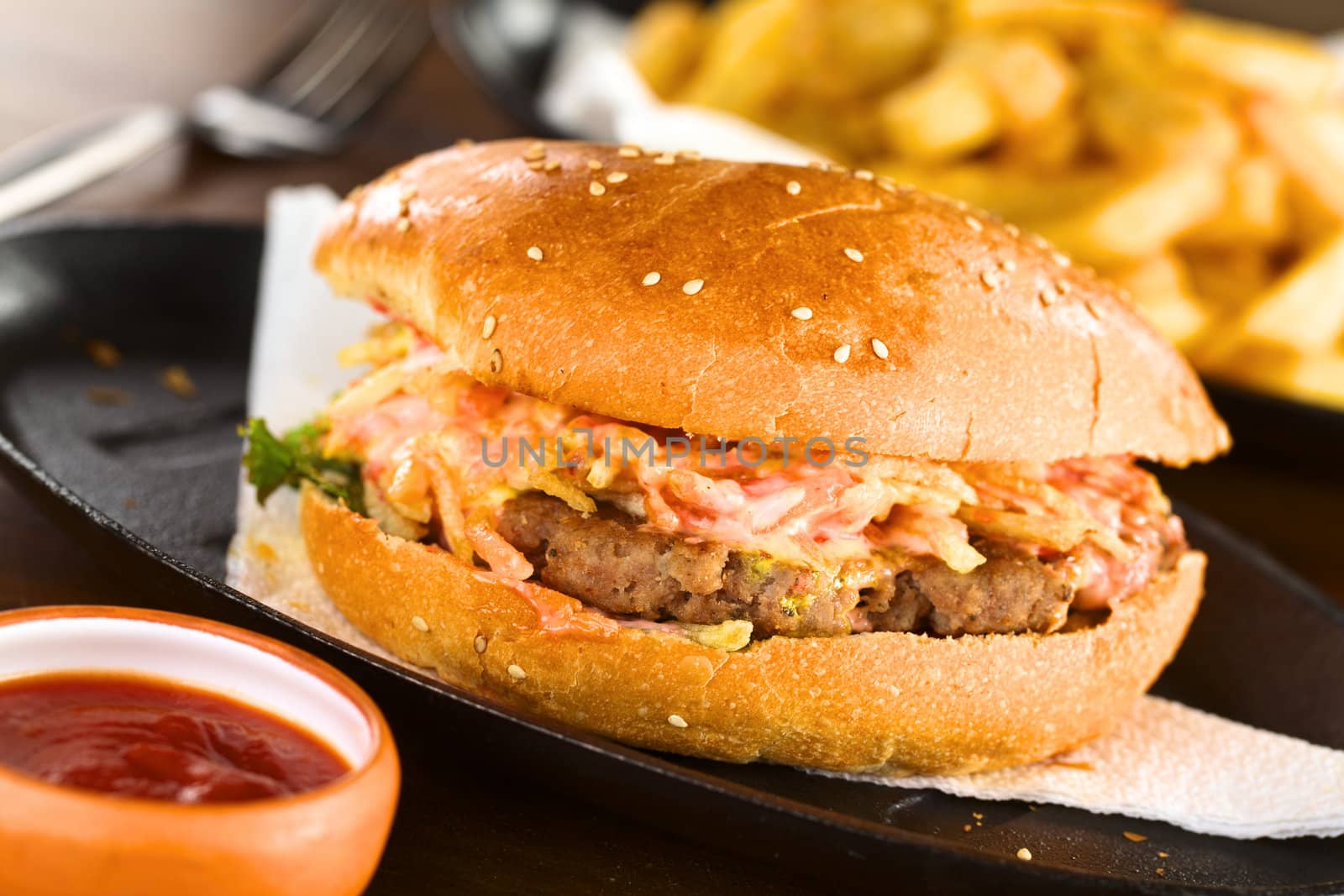 Hamburger on metallic plate with ketchup and French fries (Selective Focus, Focus on the front of the hamburger)