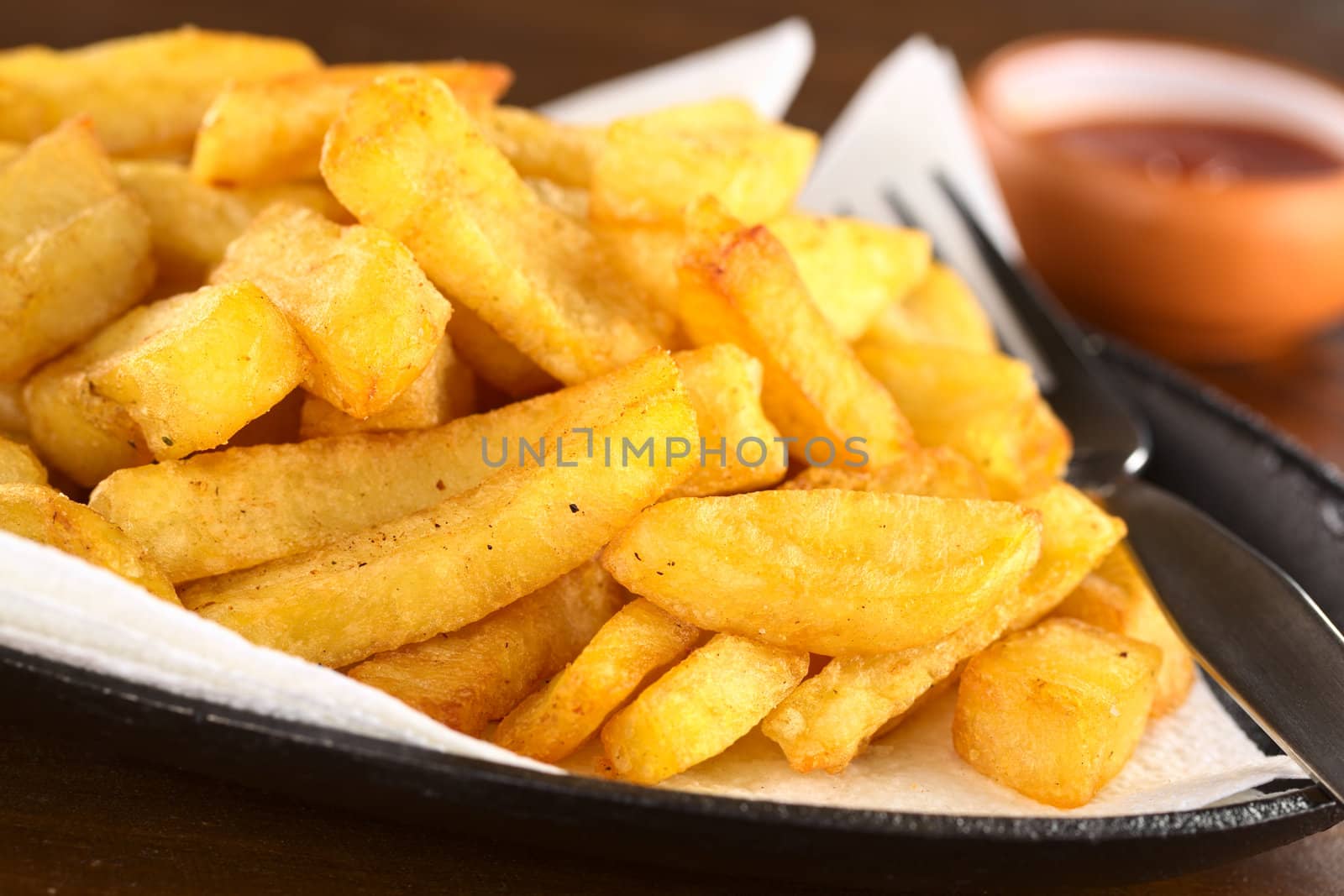 Fresh crispy homemade French fries on metallic plate with ketchup (Selective Focus, Focus one third into the fries)