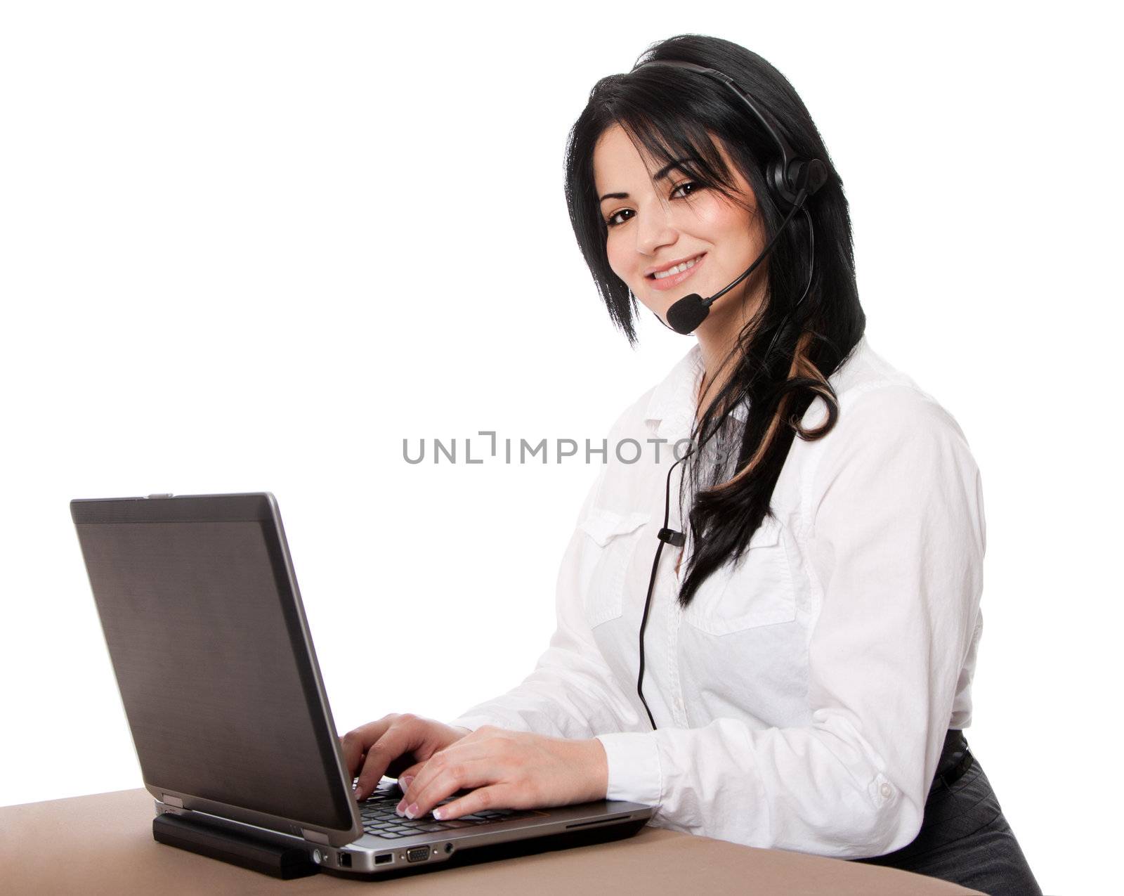 Beautiful happy customer service representative at call center office desk with headset and laptop computer online chatting, isolated.