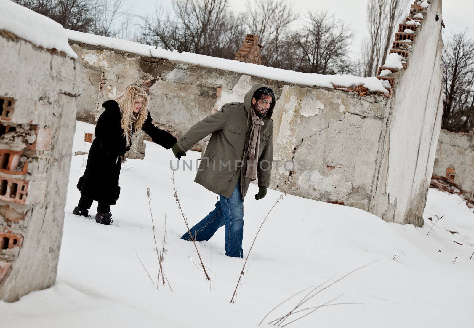 Homeless couple walking in the snow holding hands by vilevi