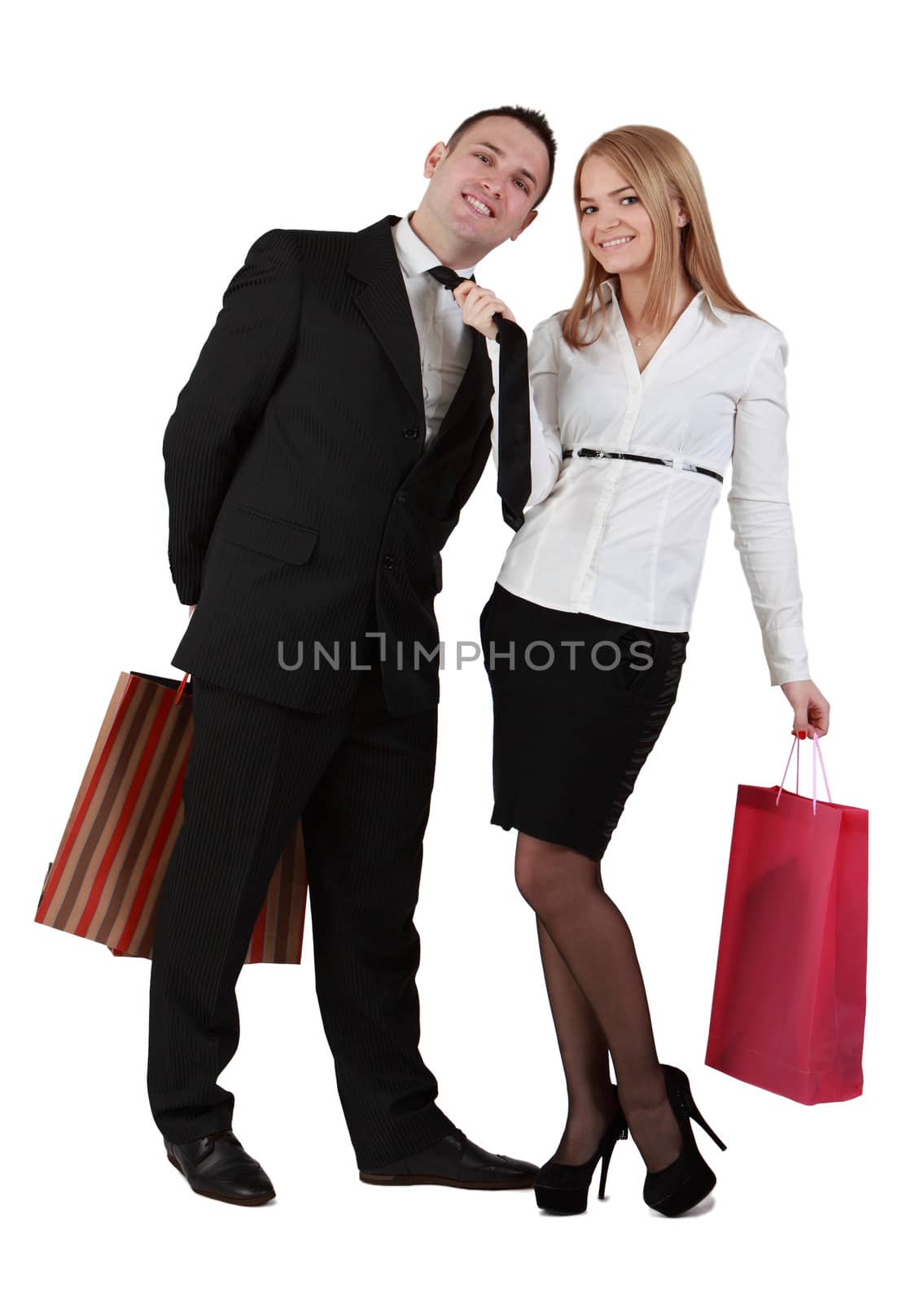Image of a young couple with shopping bags having fun while the woman pulls her boyfriend tie.