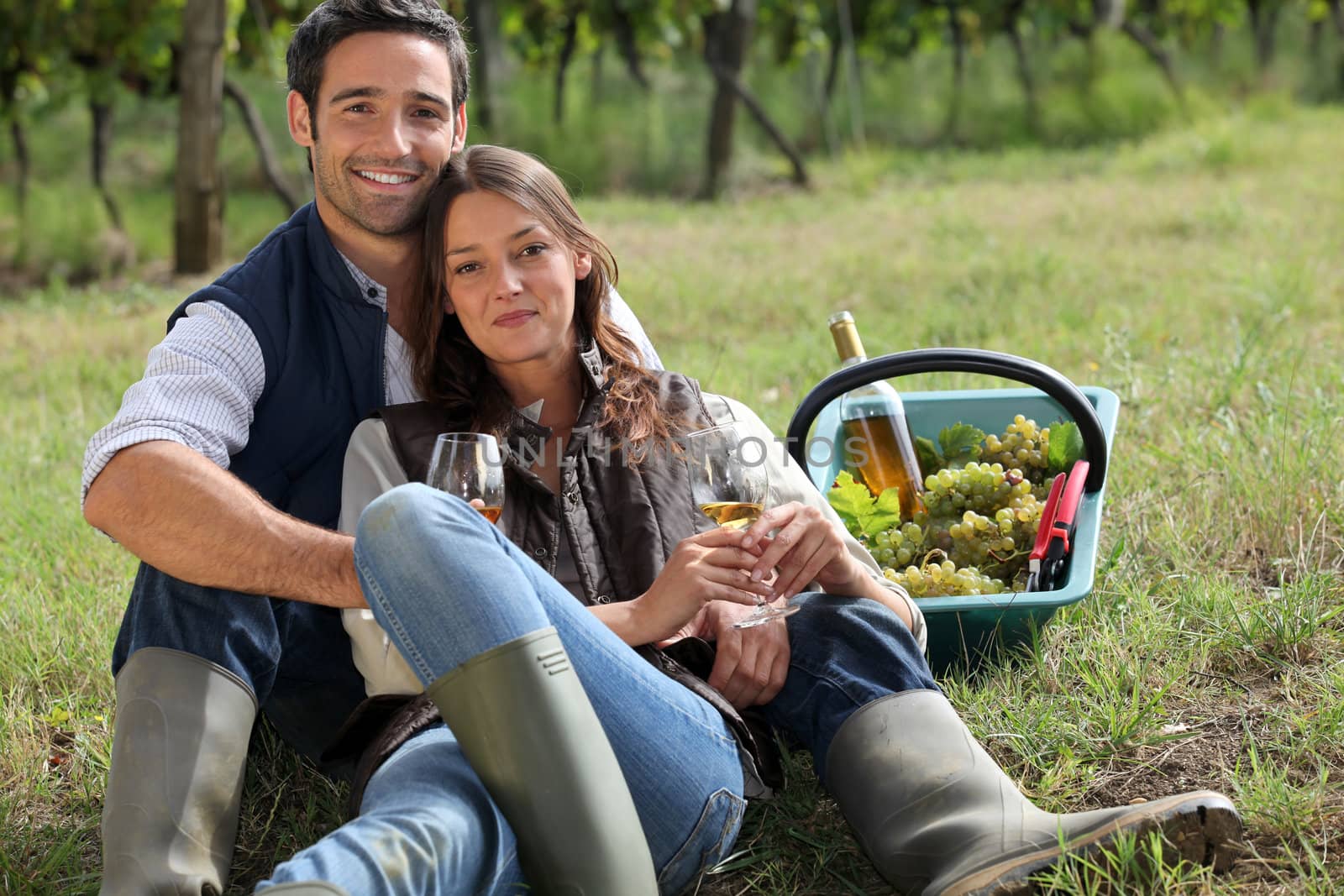 Couple having a picnic in a vineyard by phovoir