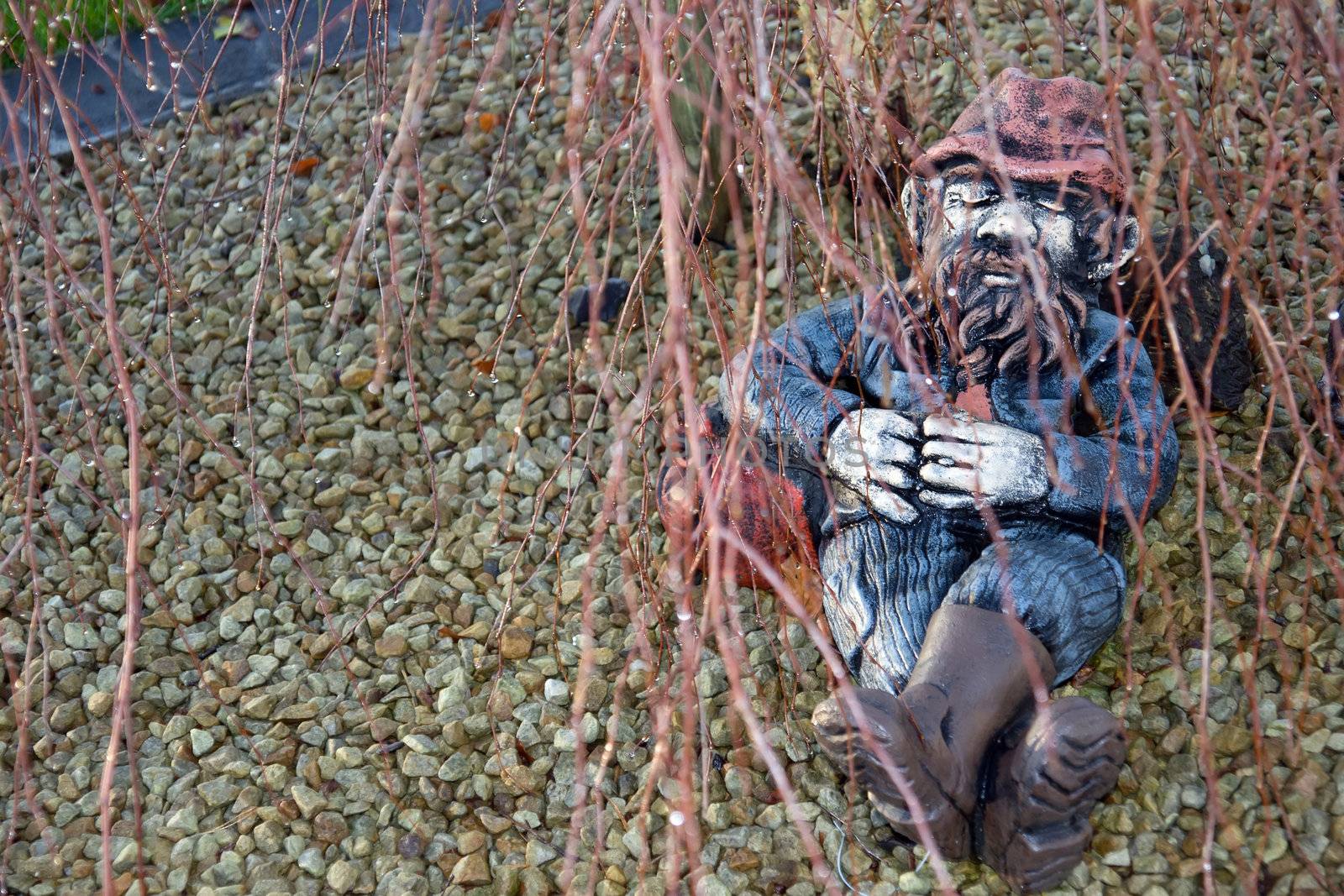 a stone man sleeping in the shade under a tree