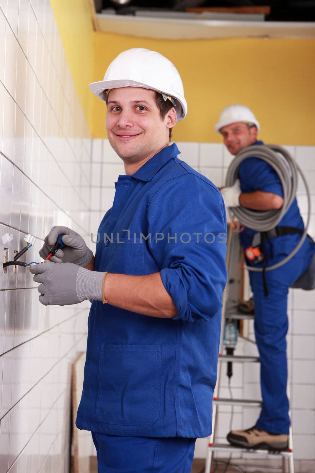 Electricians working in a tiled room