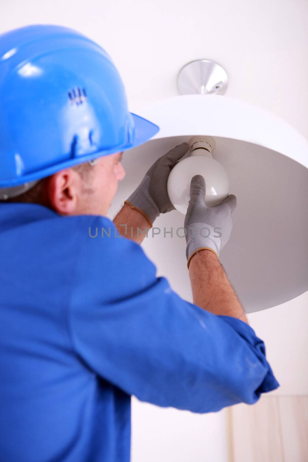 Electrician fitting a ceiling light