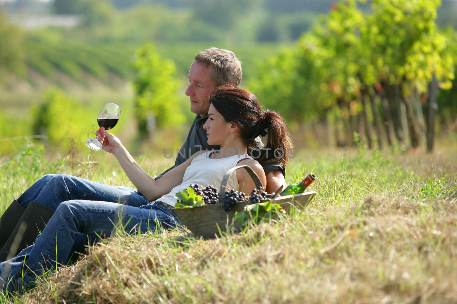 Couple tasting wine at a vineyard by phovoir