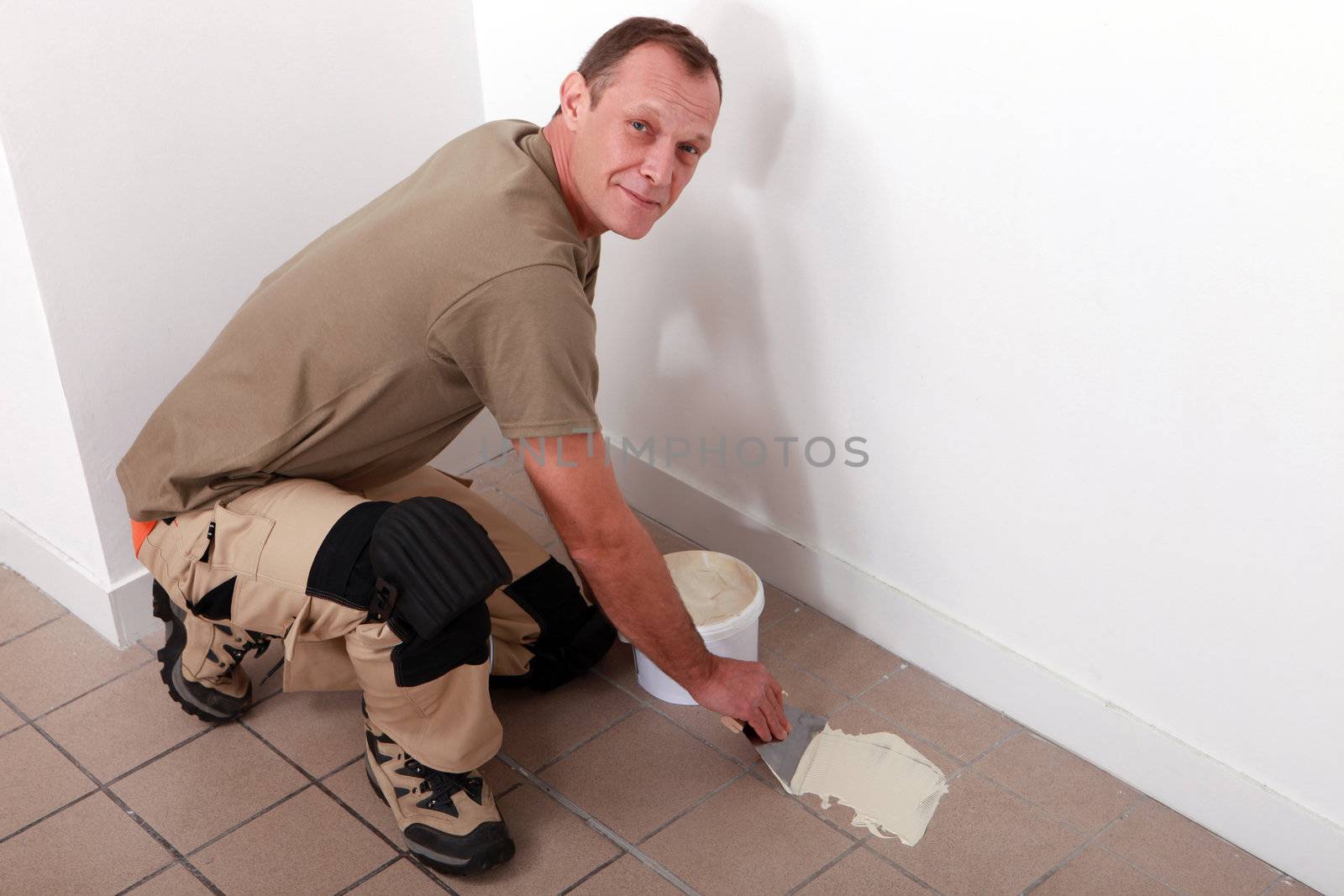 Man spreading adhesive over old floor tiles