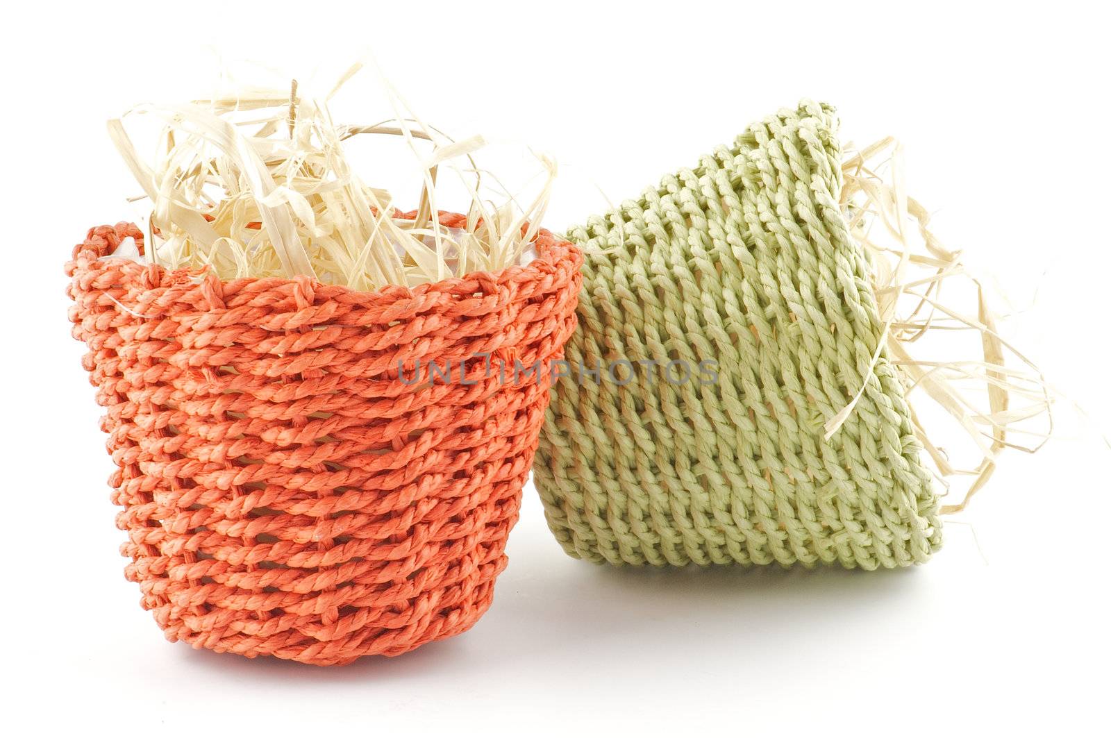 Green and red little wicker flower pots with straw isolated on white background