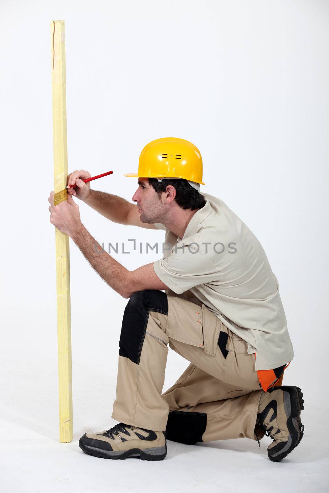 Tradesman marking a measurement on a wooden plank