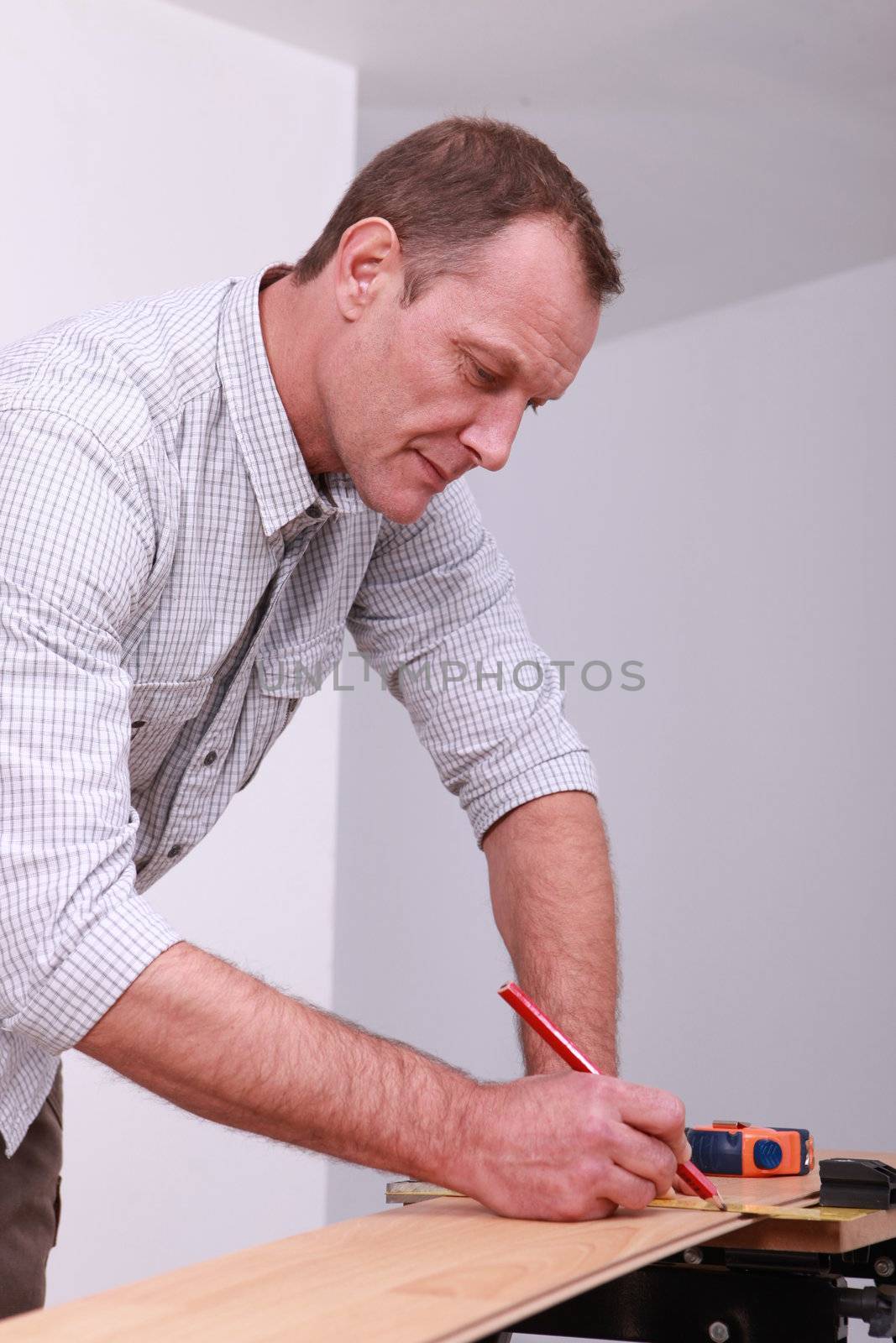 Man marking a floorboard with a pencil