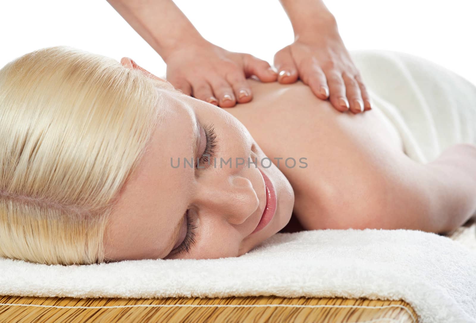 Attractive young lady relaxing on white and getting a spa massage