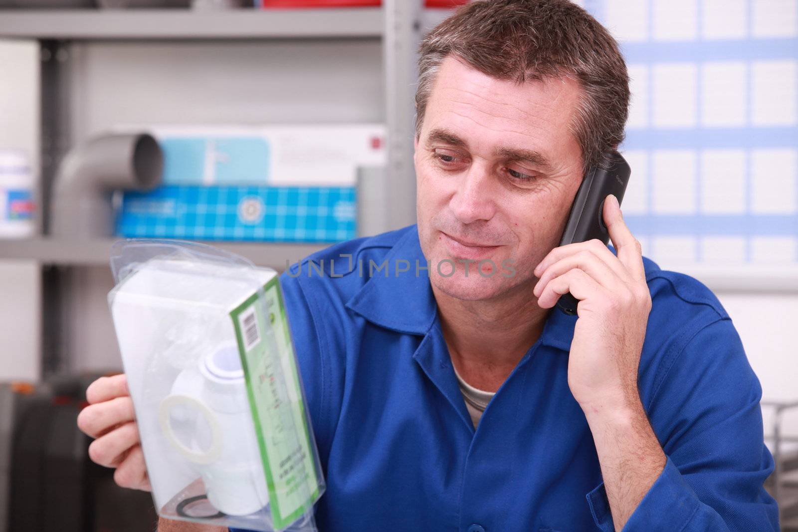 Plumbers merchant on the phone with a part in hand