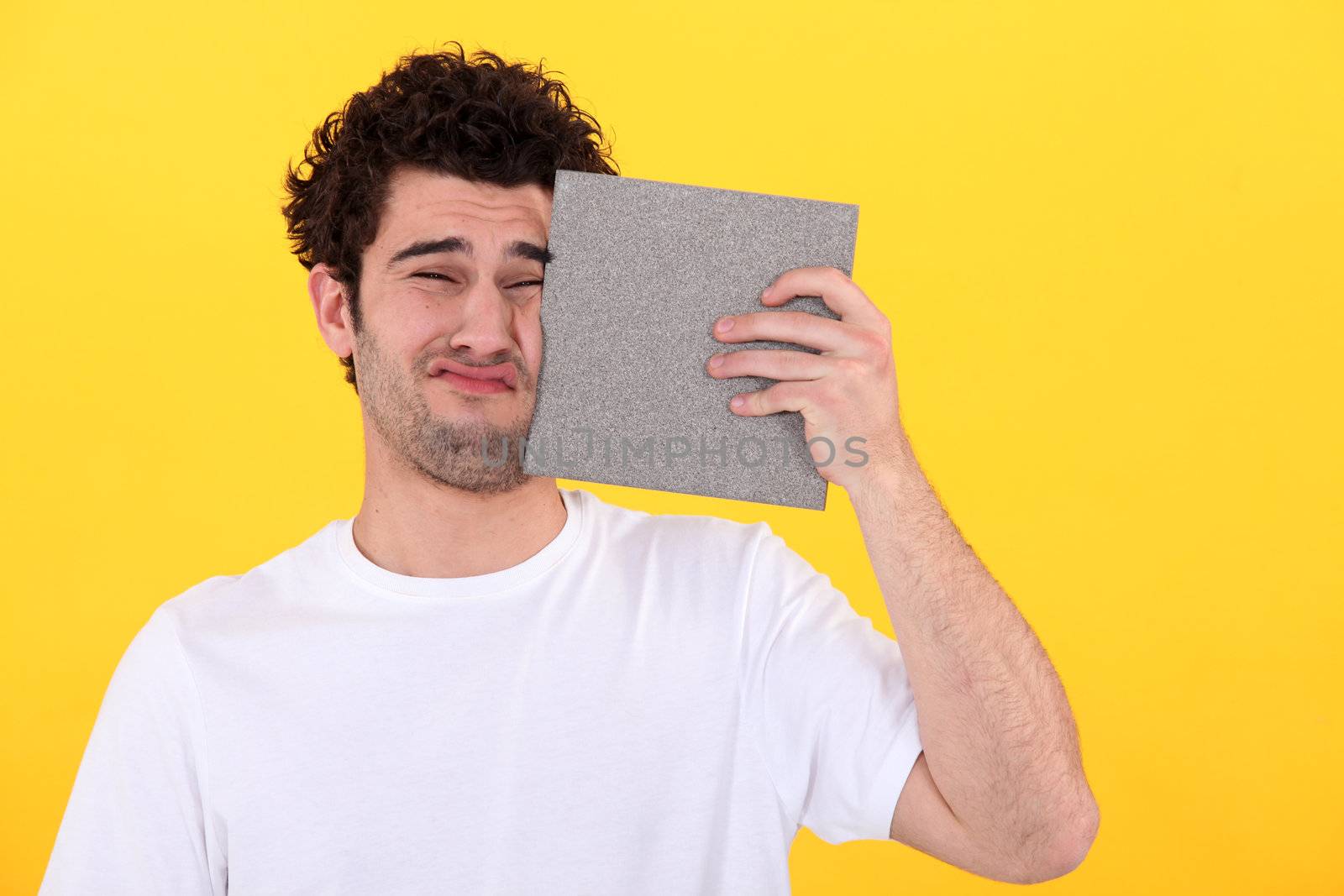 Man pressing tile against face