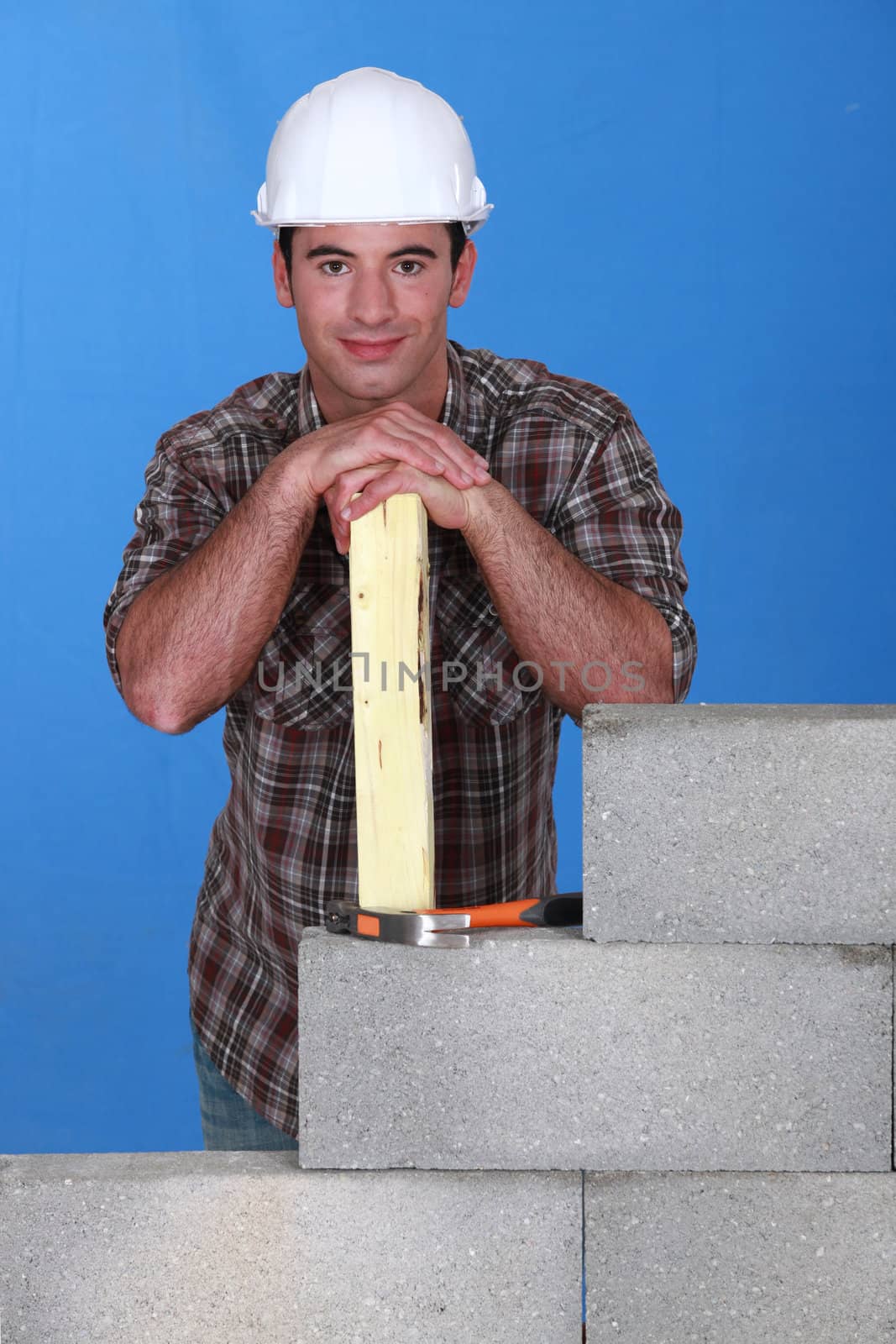 Mason stood with plank behind unfinished wall