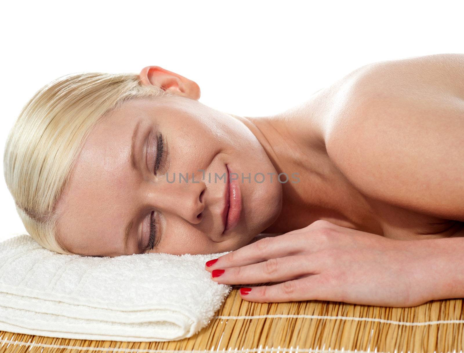 Beautiful young spa lady relaxing with head on white towel pillow