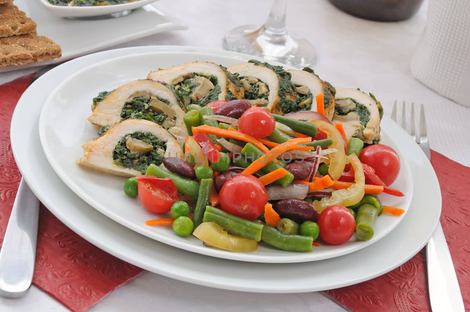 Sliced chicken roll with spinach and mushrooms garnished with vegetables