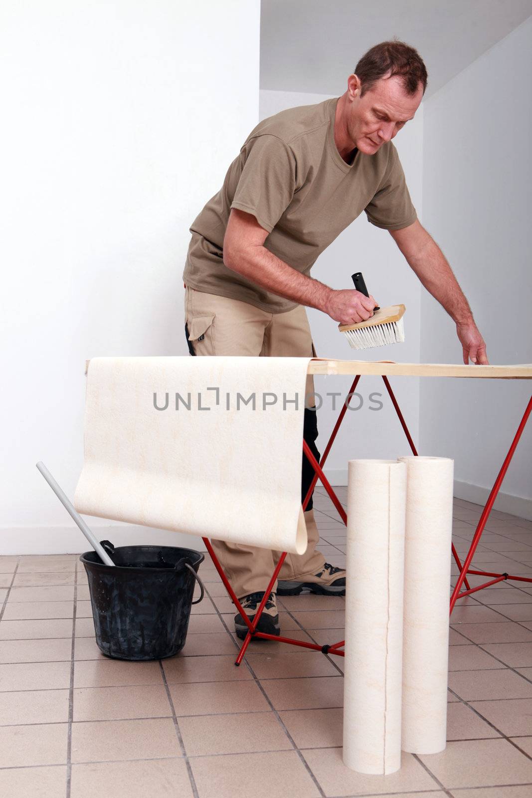 Man putting glue on wallpaper