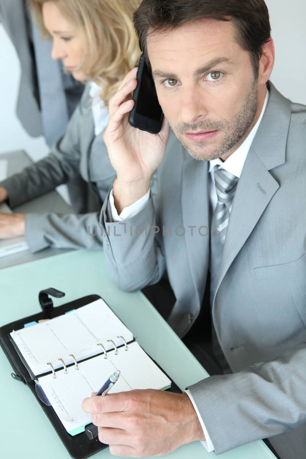 Businessman with mobile telephone and note pad by phovoir