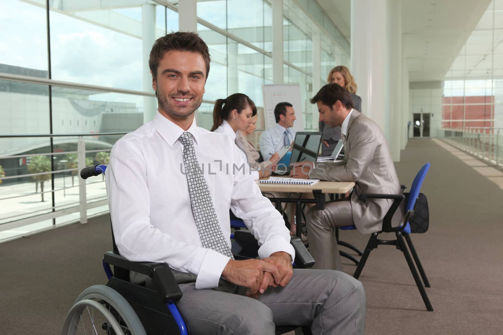 Disabled office worker with colleagues by phovoir