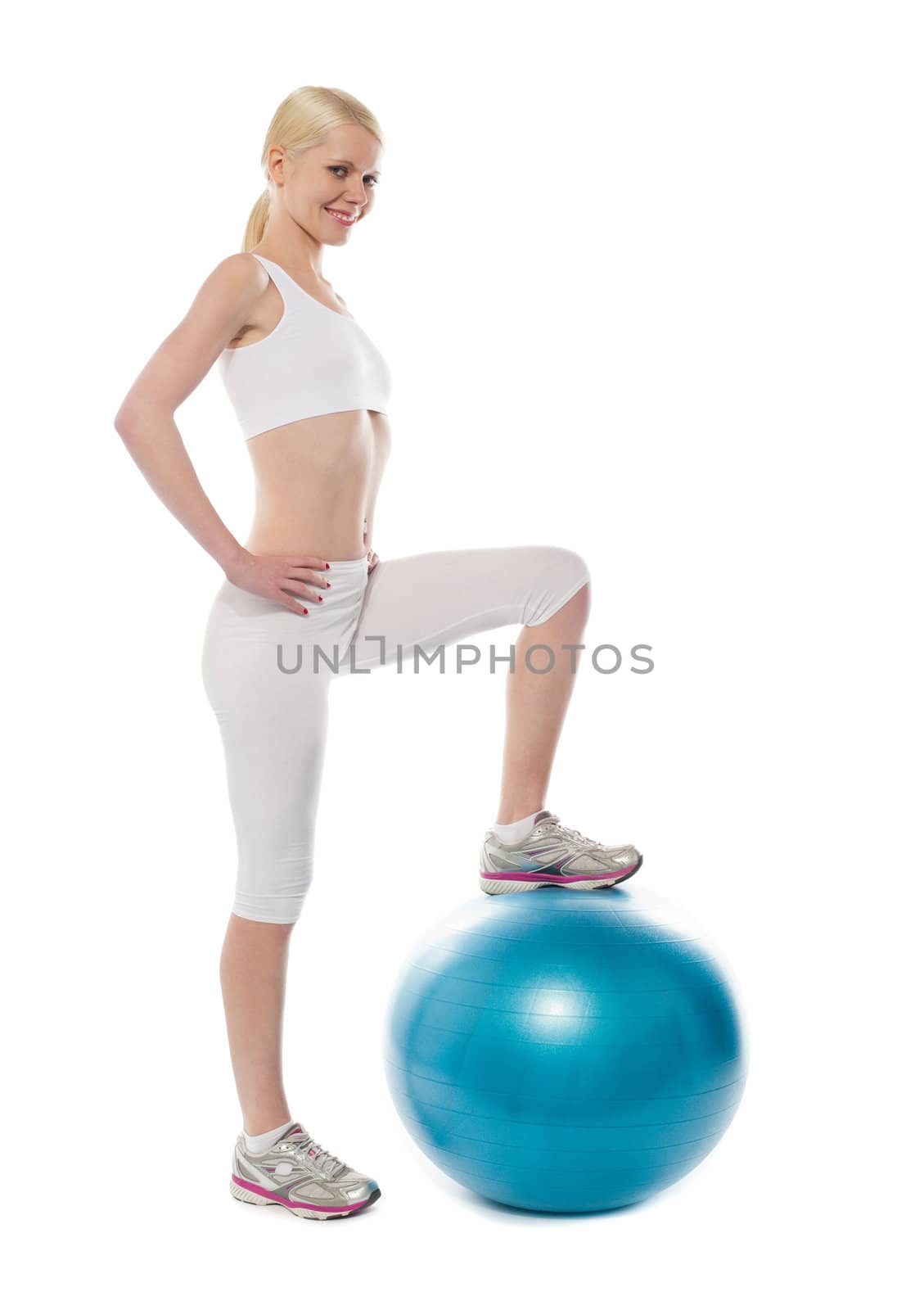 Pretty young athlete posing with foot on a blue big ball