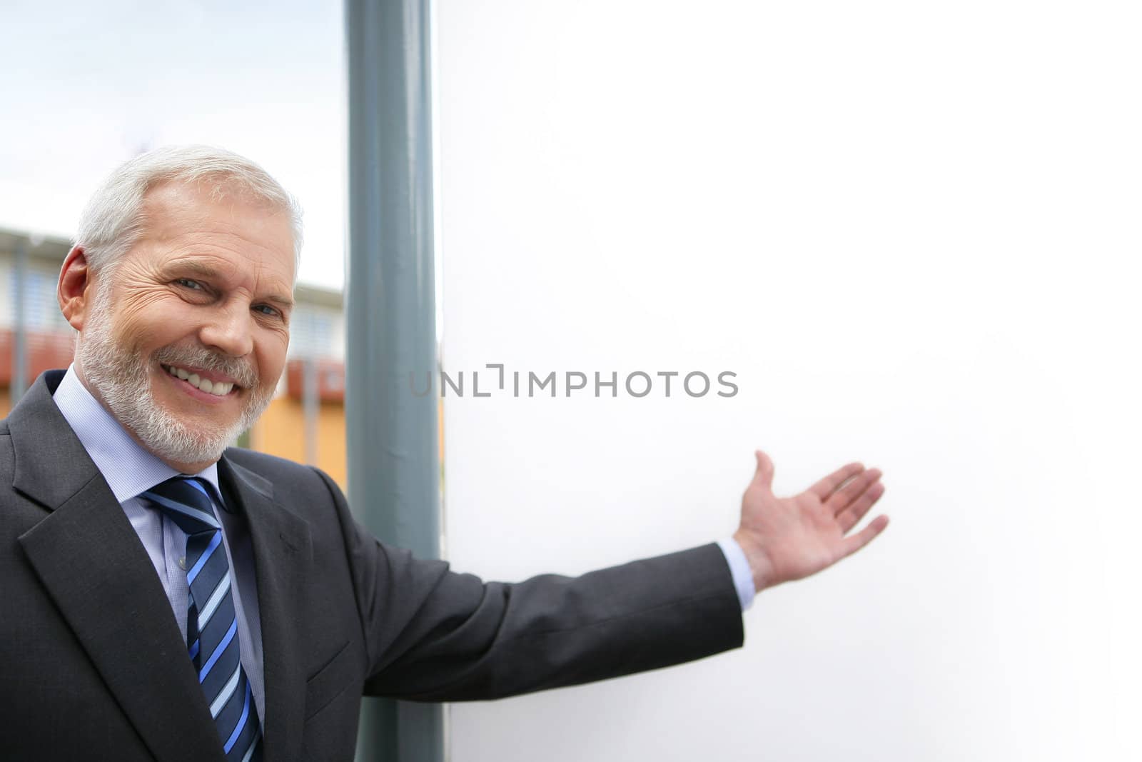 Senior businessman drawing attention to blank poster