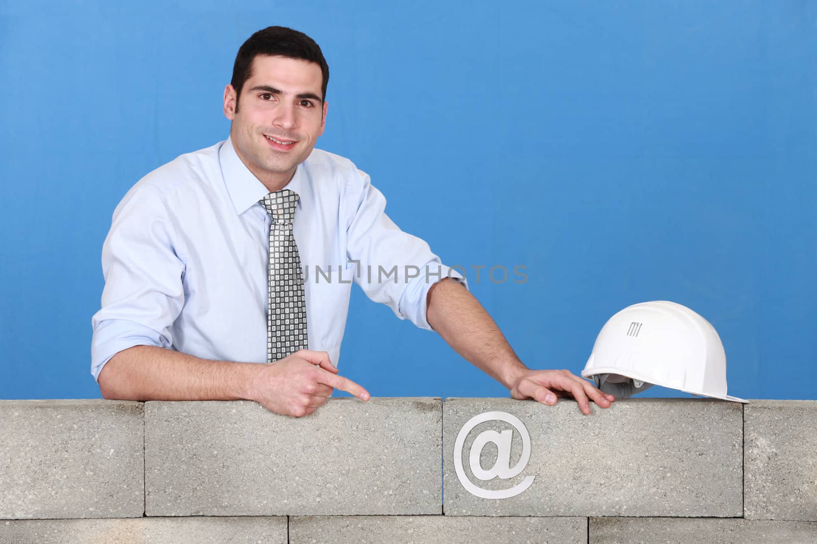 businessman pointing at an at sign on a wall