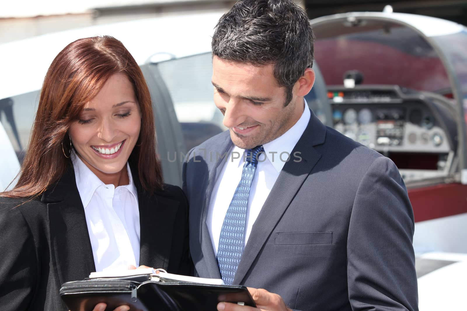 Smiling businesspeople reading notes by phovoir