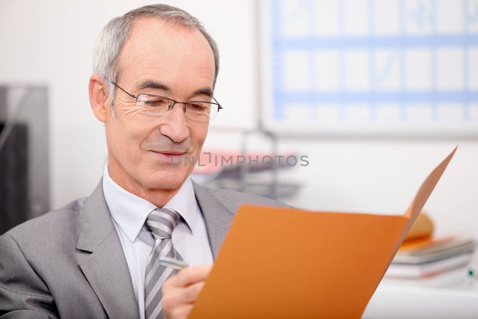 Older businessman writing in a file